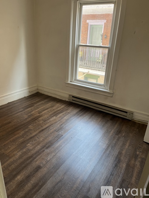 A room with a window and wooden flooring.