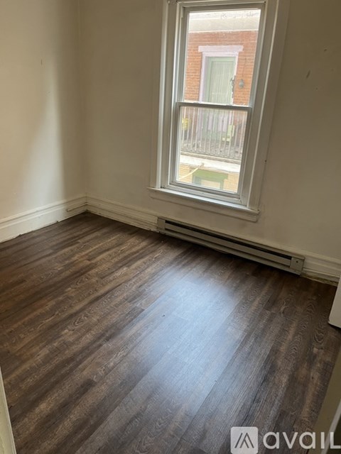 A room with a window and wooden flooring.