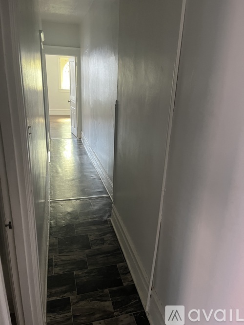 A long hallway with a tiled floor and white walls.