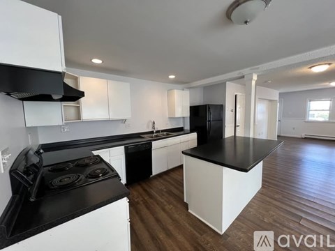A modern kitchen with black countertops and white cabinets.