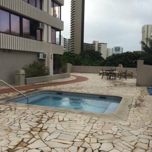 A pool surrounded by a stone patio.
