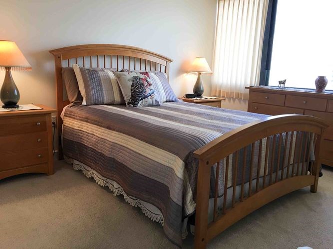 A bed with a wooden headboard and pillows is in the center of the room.
