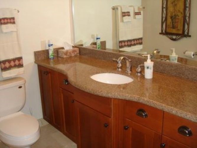 A bathroom with a brown counter top and a white toilet.