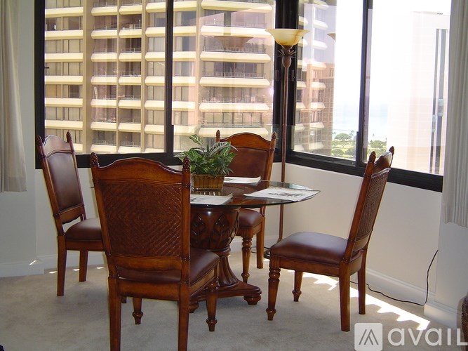 A brown wooden table with four chairs in front of a window with a view of a building.