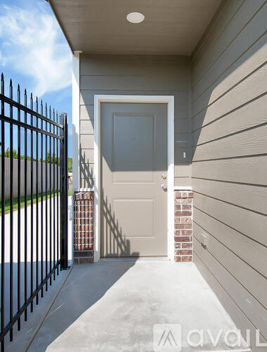 A black metal gate is on the left of a white door.