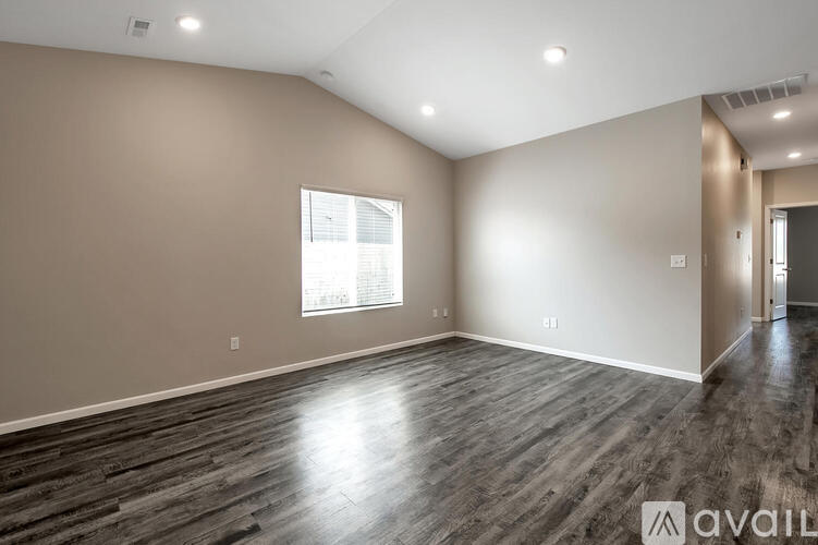 A spacious room with wooden flooring and a window.