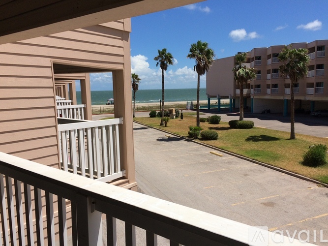 A view from a balcony overlooking a parking lot and beachfront buildings.