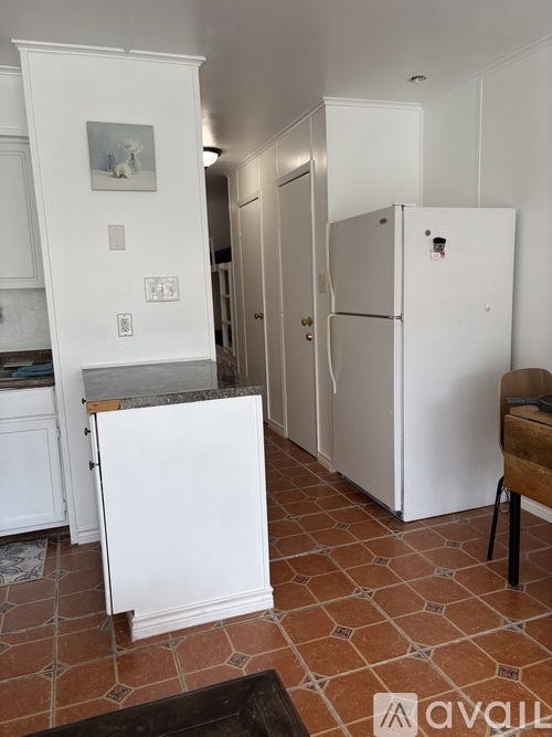 A kitchen with a white fridge and a marble counter top.