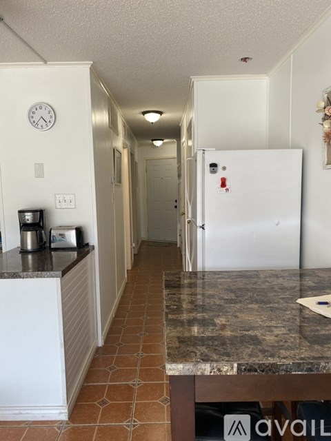 A kitchen with a white fridge and a marble counter top.