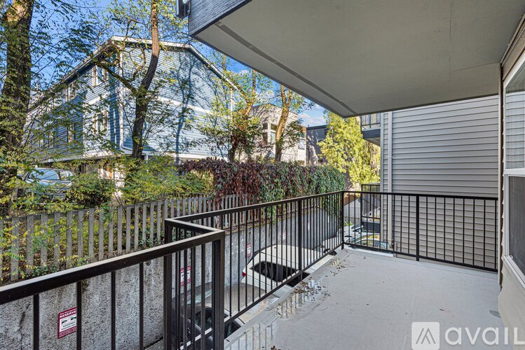 A balcony with a black railing and a view of a house and trees.