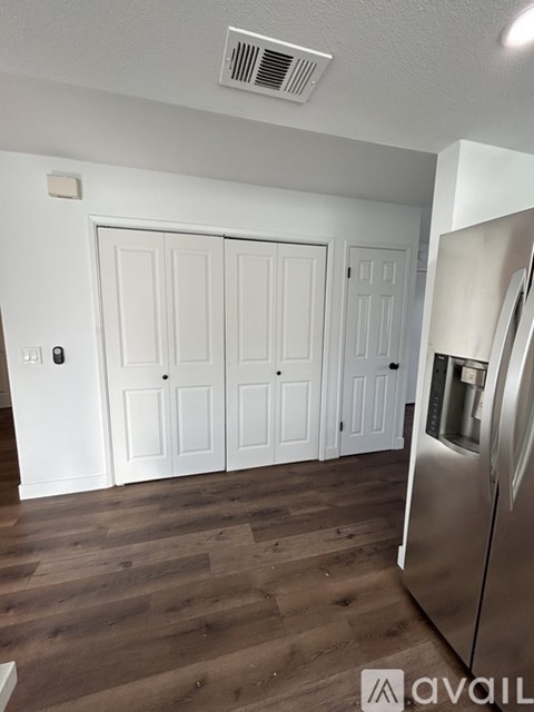 A kitchen with white cabinets and a stainless steel refrigerator.