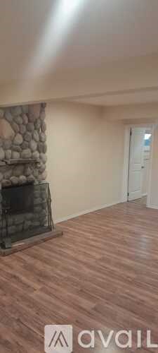 A room with a stone fireplace and wooden flooring.
