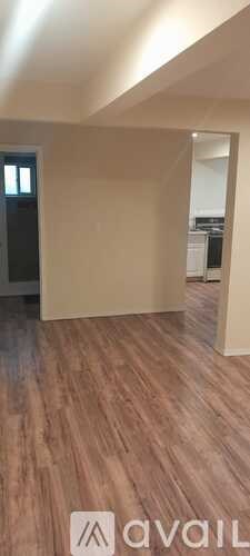 A room with wooden flooring and a door on the left side.