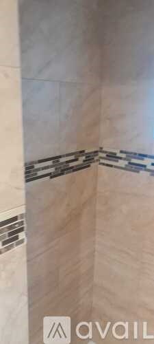 A bathroom with a tiled edge and a beige wall.