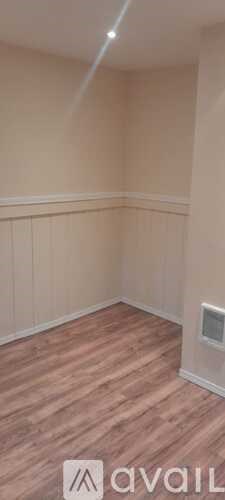 A room with wooden flooring and a wall with a window.