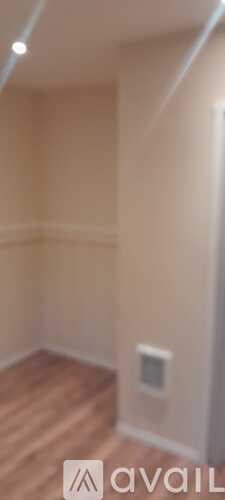 A room with wooden flooring and beige walls.