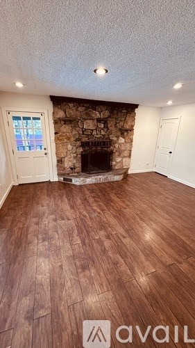 A room with a stone fireplace and wooden flooring.