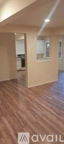 A room with wooden flooring and a wall with a window.
