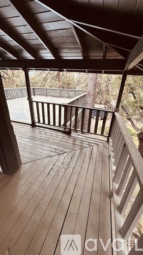 A wooden deck with a railing and a view of trees.