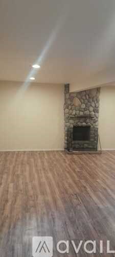 A room with a stone fireplace and wooden flooring.