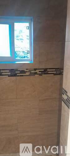 A bathroom with a window and tiled walls.