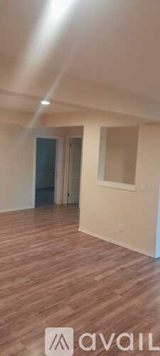 A room with wooden flooring and a doorway leading to another room.