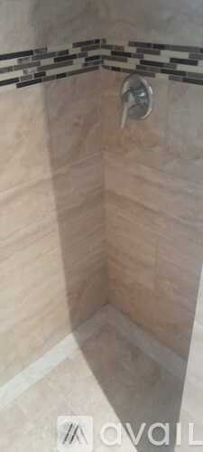 A shower area with a tiled wall and a shower head.