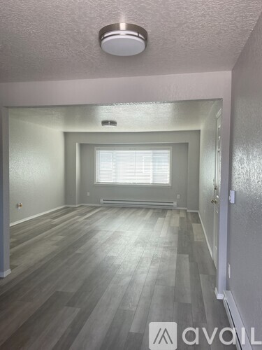 A room with wooden flooring and a window with blinds.