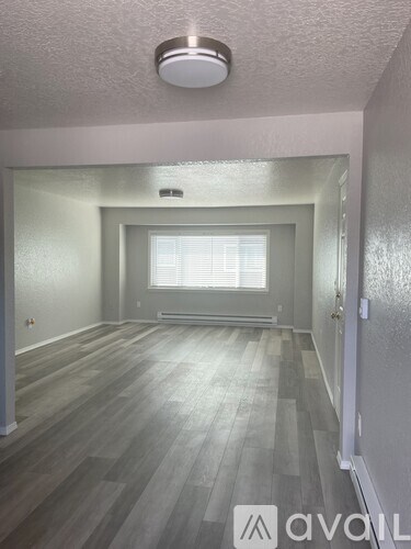 A room with wooden flooring and a window with blinds.