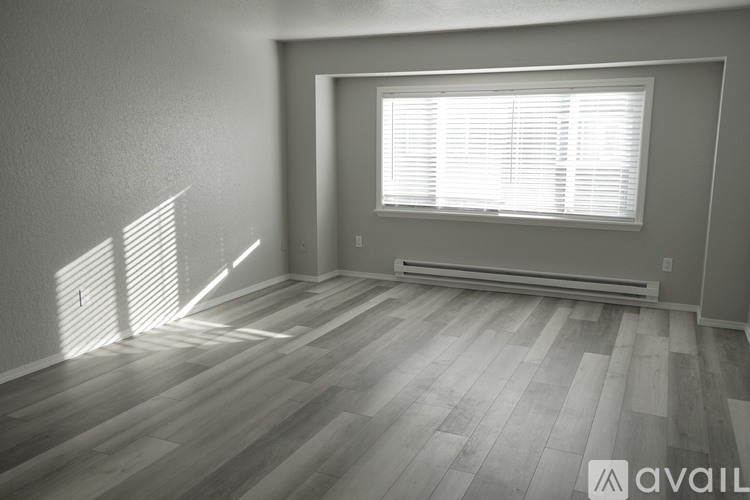 A room with wooden flooring and a window with blinds.