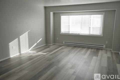 A room with wooden flooring and a window with blinds.