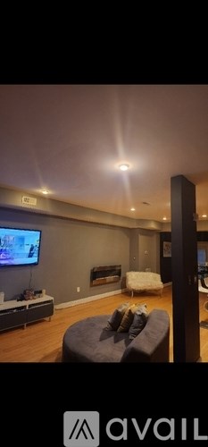 A living room with a grey couch and a television on the wall.