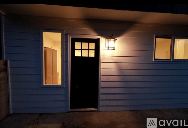 A house with a black door and windows is illuminated by a single light source.