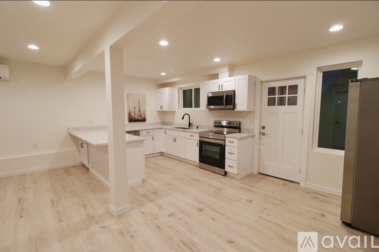 A modern kitchen with white cabinets and a wooden floor.