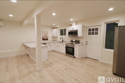 A modern kitchen with white cabinets and a wooden floor.