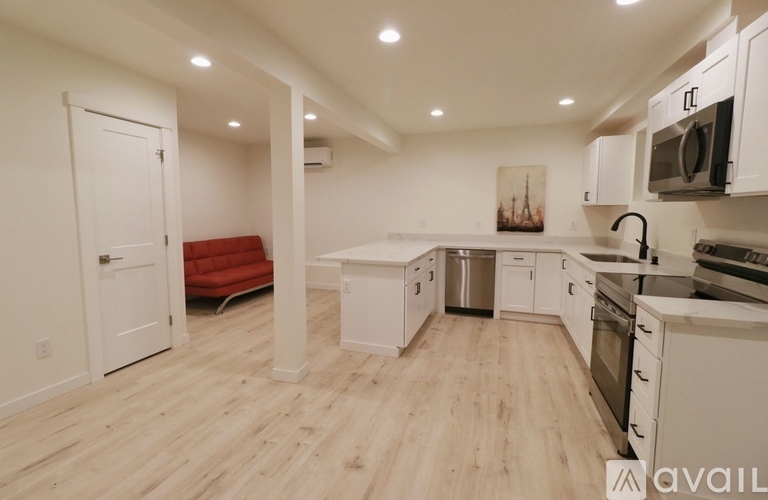 A kitchen with white cabinets and a red couch.