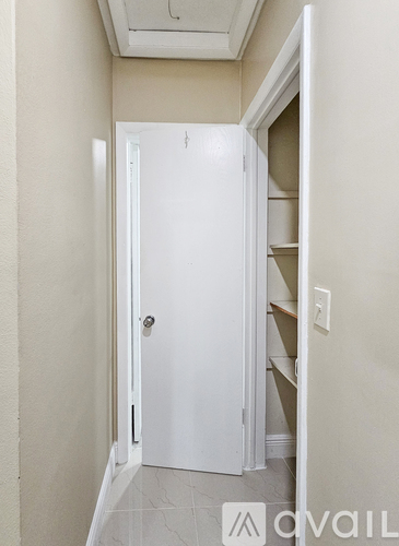 A white door is open to a hallway with a light switch on the wall.