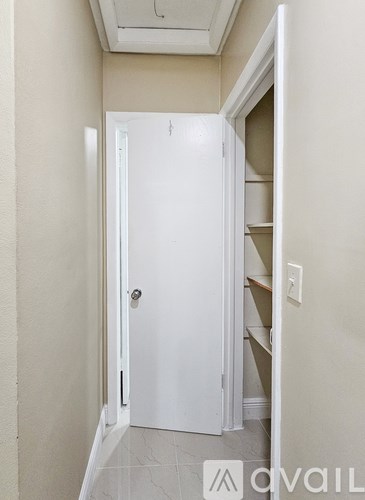 A white door is open to a hallway with a light switch on the wall.