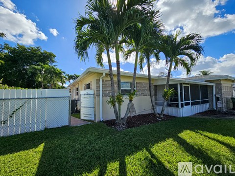 A house with a white fence and palm trees in front.