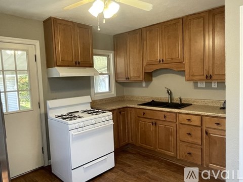 A kitchen with a white stove and wooden cabinets.