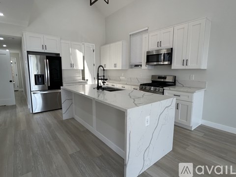 A kitchen with white cabinets and a marble island.