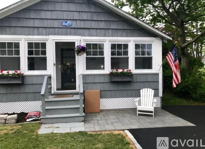 A small house with a porch and an American flag.