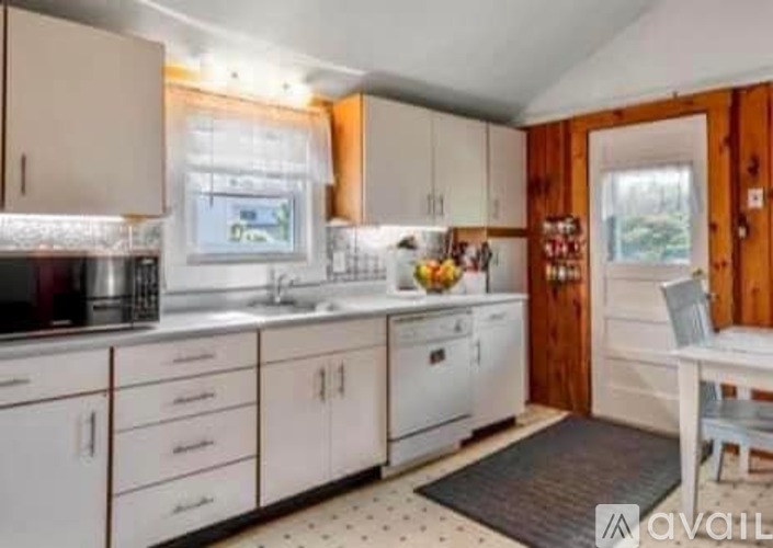 A kitchen with white cabinets and a wooden door.
