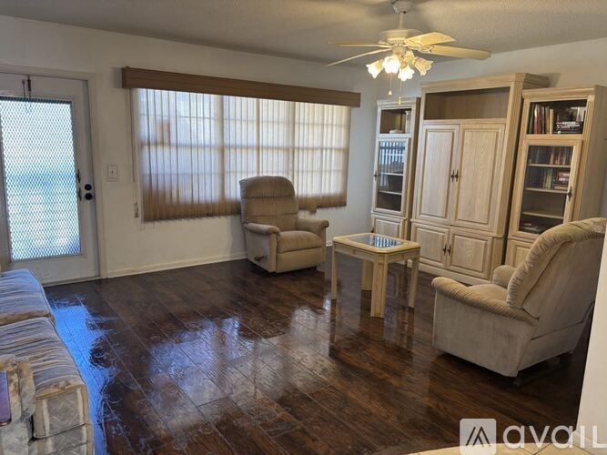 A living room with a wooden floor and a ceiling fan.