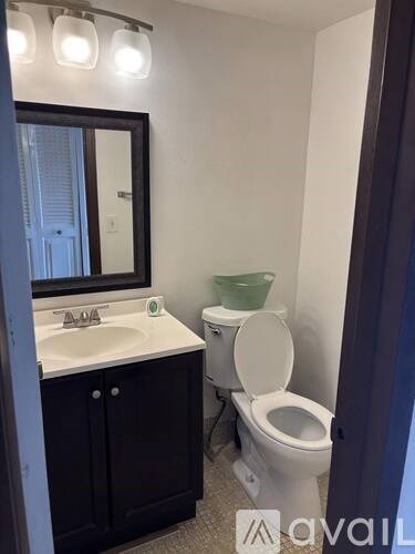 A bathroom with a toilet, sink, mirror, and cabinet.