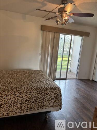 A bedroom with a leopard print bedspread and a ceiling fan.