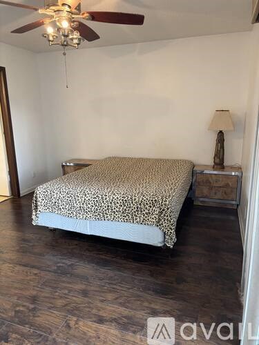 A leopard print bedspread on a bed in a room with a ceiling fan.