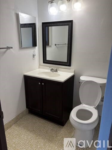 A bathroom with a toilet, sink, and mirror.