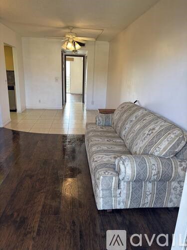 A living room with a striped couch and a ceiling fan.