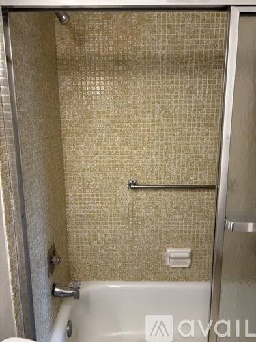 A bathroom with a beige tiled shower and a white bathtub.